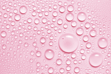 Water drops texture background. Pink toner spray, face mist, serum, liquid skin care product closeup