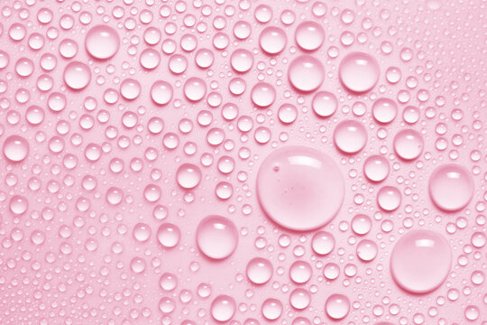 Water drops texture background. Pink toner spray, face mist, serum, liquid skin care product closeup