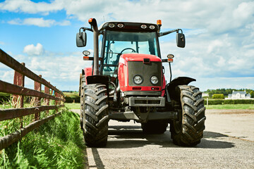 Obraz premium Outdoor, farm and agriculture with tractor for tiling, plowing and cultivation of soil for crop growth. Blue sky, nature and machine truck in countryside for harvesting, planting and sowing of seeds