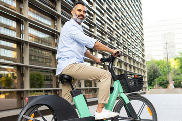 From below an Indian man commuting on electric bike in urban setting