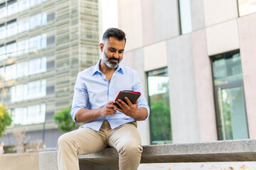 Indian businessman using tablet outdoors in the city