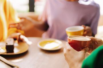 Women talking and enjoying coffee and cake in cafe selective focus, closeup