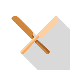 Two crossed wooden butter knives casting a long shadow on a white background