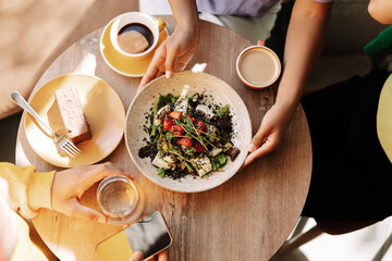 Top view three friends sharing healthy vegan lunch in a modern restaurant