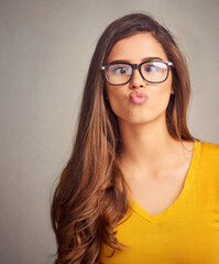 Obraz premium Studio, woman and silly with pout for goofy, funny expression and face humor with positive attitude. Female model, glasses and playful with emoji reaction by isolated background, comedy and pose