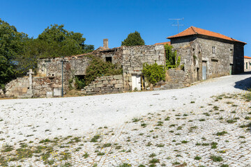 Old abandoned granite Portuguese house with religious christianity cross and blue sky