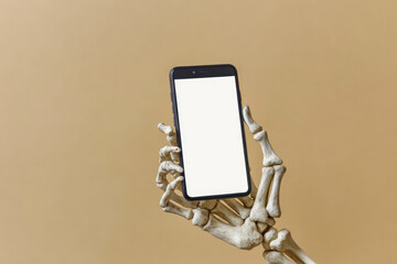 Skeleton hand holding smartphone with blank screen on beige background