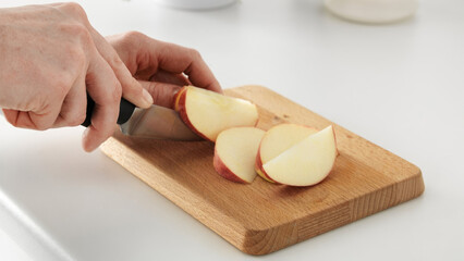 Closeup of a person dicing apples on a wooden cutting board.