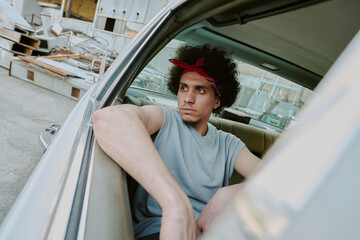 Dutch angle shot of young man immersed in thoughts while sitting in car