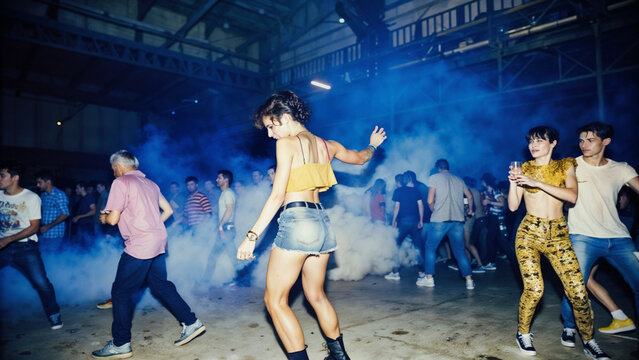 Graceful dancers with flowing yellow fabric performing in misty warehouse party atmosphere