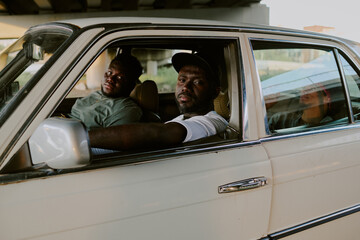 Brutal and tough men sitting in old car and looking directly at camera