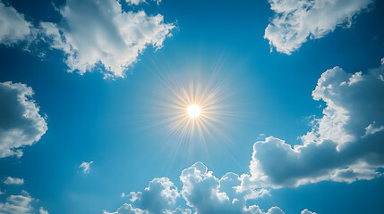 Bright sun shining through fluffy clouds on a clear blue sky