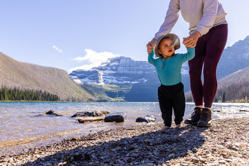 Mother Helping Baby Walk by Scenic Mountain Lake Shore