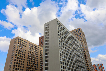 New residential buildings on background of blue sky with white clouds. House development, high-rise construction