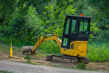 A mini-excavator on the park background   Minikoparka na tle parku © Adrian White