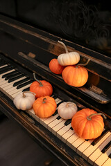 old shabby piano decorated with orange and white pumpkins. halloween celebration concept, dark...