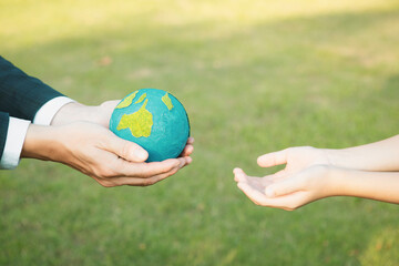 Businessman hand giving Earth globe to little boy as Earth day concept as corporate social responsible to contribute greener environmental protection for sustainable future generation. Gyre