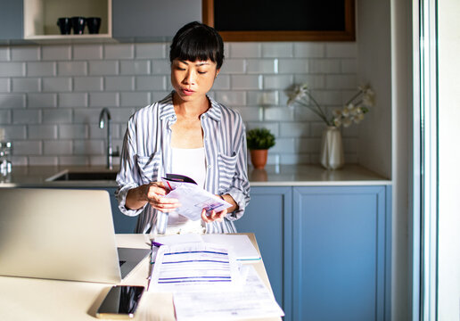 Focused woman organizing bills and paperwork in kitchen