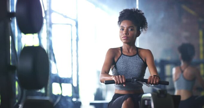 Fitness, woman and rowing machine at a gym for training, health or wellness routine. Sports, workout and female athlete with pulling exercise, energy or mindset, resilience or weight loss motivation