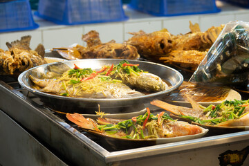 A variety of fish dishes are displayed on a table, including some with vegetables. The presentation is colorful and appetizing, and the dishes are arranged in a way that makes them easy to access