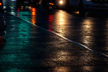 A wet road with cars and motorcycles in the background. The image has a moody and somewhat ominous...