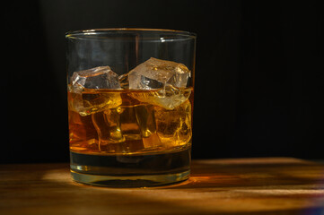 a glass of scotch whisky with back lighting. tumbler of whiskey / brandy and ice backlit scotch on the rocks