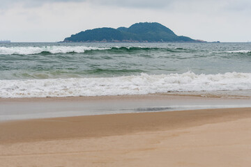 The Tombo beach of Guaruja - SP, Brazil with the Farol da Moela island on background. Landscape of the beach with no people.