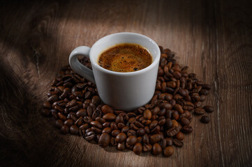 Obraz premium Fragrant hot coffee in a white cup with beans spilling roasted c