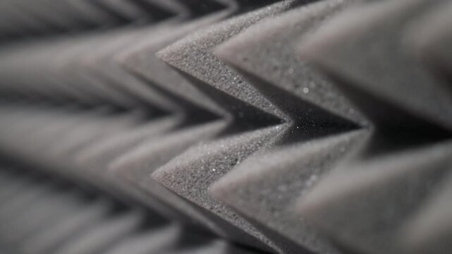 Close-up view of pyramid-shaped acoustic foam panels designed for sound absorption. Ideal for studio or audio setup, showcasing detailed texture and effective soundproofing