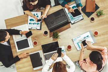 Top view of businessman executive in group meeting with other businessmen and businesswomen in modern office with laptop computer, coffee and document on table. People corporate business team uds