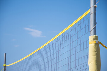 the ball flies through the net against the background of a clear blue sky, beach volleyball in the sea or ocean in summer, ball matches and active activities, copy space