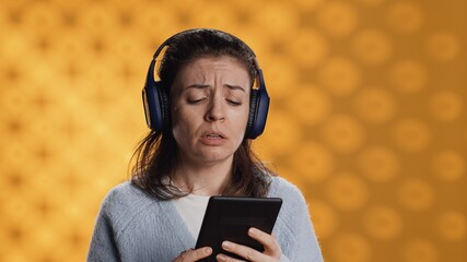 Voice actor frowns while reading ebook, portraying character, studio background. Woman reenacting...