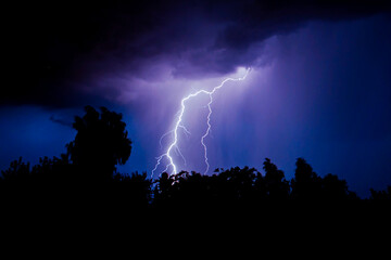 beautiful lightning during a thunderstorm at night in a forest that caused a fire, against a dark sky with rain