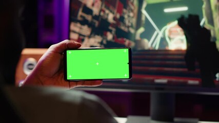 Man watching favorite content creator on isolated screen smartphone showing tips for game he is currently playing. Player looking online for inspiration on mockup phone, stuck on mission