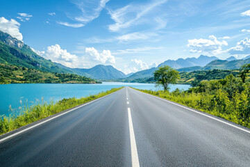 Fototapeta premium Asphalt highway road and blue lake with mountain nature landscape under blue sky.