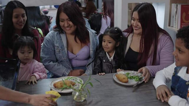 Waiter serving a delicious plate of peruvian cuisine to a joyful family at a restaurant