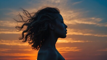 Silhouette of a woman with wavy hair at sunset sky background.