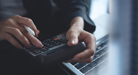 Closeup of business woman, accountant working at office, using calculator to calculate home...