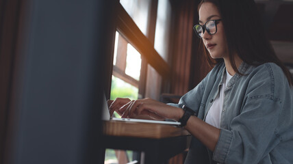 Asian woman working on laptop computer at coffee shop. Young female freelancer online working at cafe. Student online studying, surfing the internet on laptop, e-learning, remote work, close up