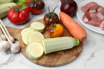 Different vegetables and raw meat for stew on white marble table