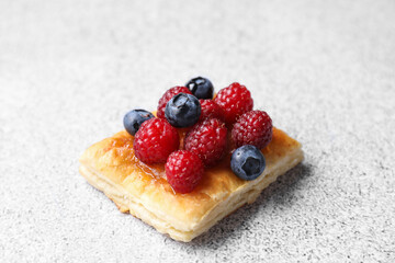 Tasty puff pastry with berries on light grey table, closeup