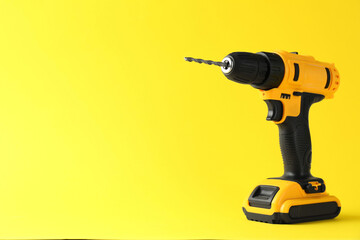 Modern cordless electric drill on yellow background. Space for text