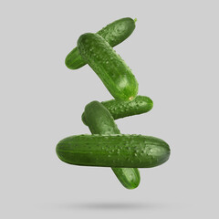 Whole ripe cucumbers falling on grey background