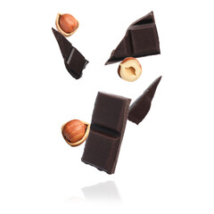 Pieces of tasty chocolate and hazelnuts falling on white background