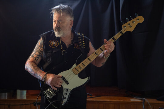 Bass Guitarist, Male caucasian with a beard and arm tattoo's playing a bass guitar looking towards the camera left, semi profile with copy space.