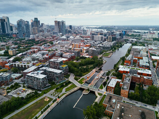 Naklejka premium Drone view of single-storey buildings between the Lachine channel and downtown Montreal skyscrapers Quebec, Canada.