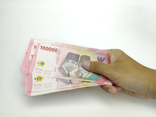 A man's hand is holding one hundred thousand Indonesian banknotes. Cash payment concept. Indonesian rupiah currency (Rp. 100,000 One Hundred Rupiah) on a white background