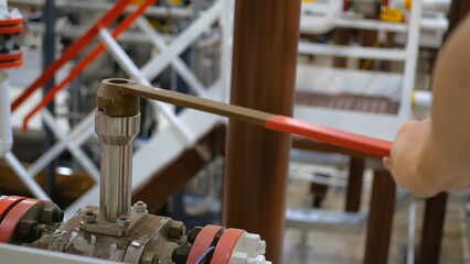 In chemical plant, worker is opening valve to resume flow of chemicals necessary for fertilizer production. operations after scheduled maintenance, production of essential agricultural products.