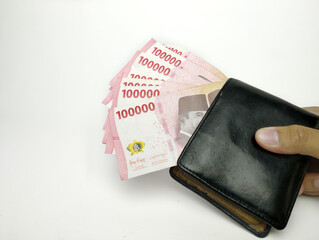 A man's hand is holding one hundred thousand Indonesian banknotes in wallet. Cash payment concept. Indonesian rupiah currency (Rp. 100,000 One Hundred Rupiah) on a white background