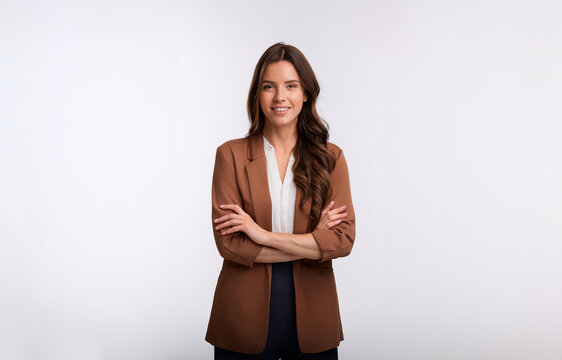 mulher morena de cabelos ondulados longos sorridente camisa social blaser bege fundo branco isolado